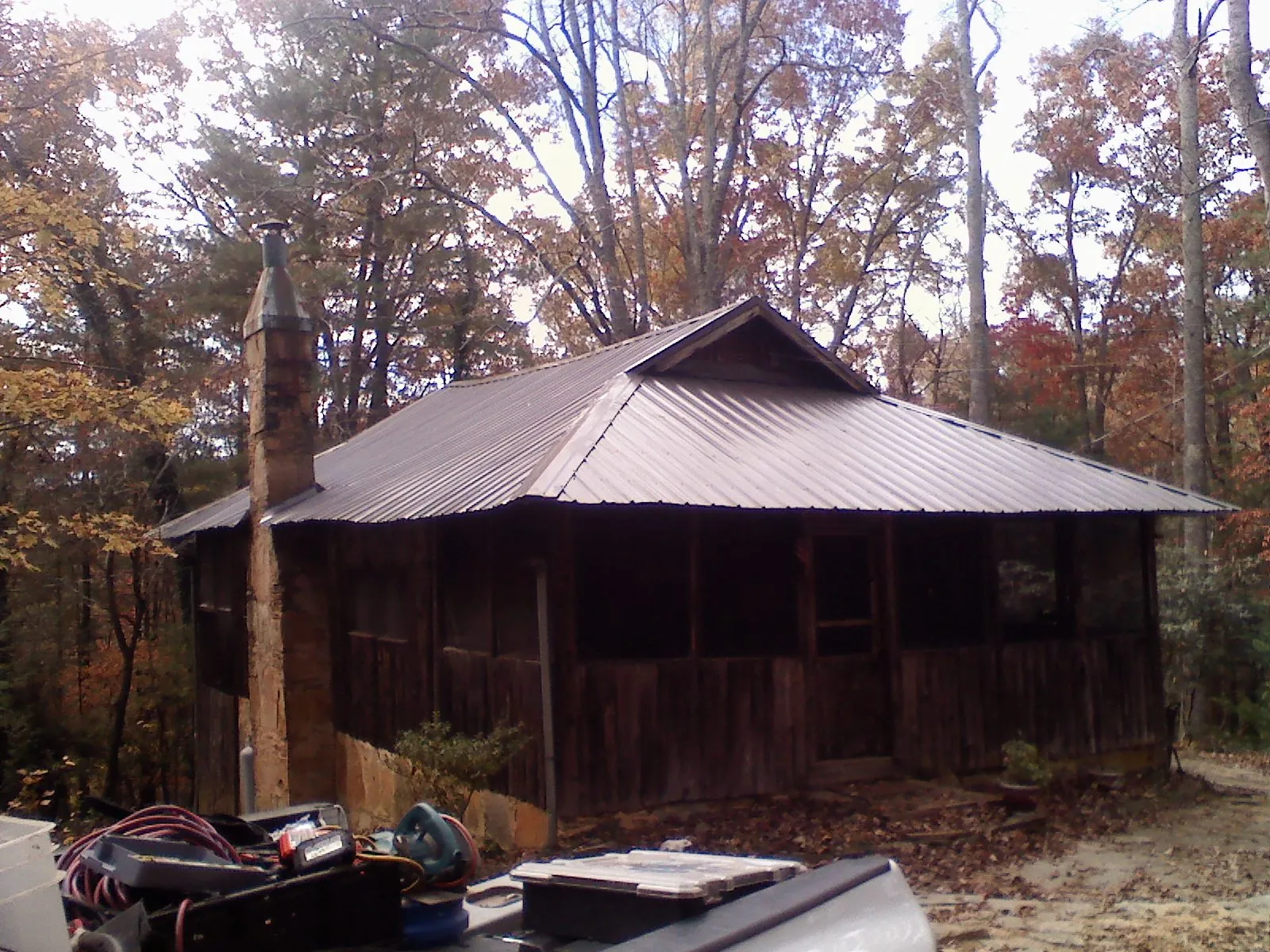 Brown metal hip roof on an old cabin with a stone chimney in Old Fort