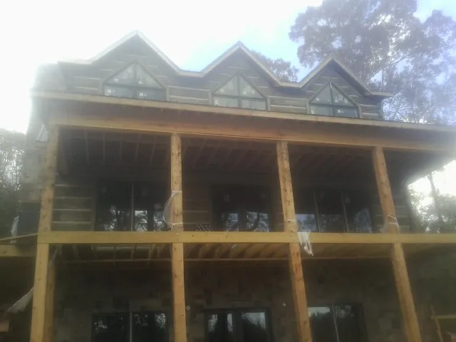 Dormers and porch framing on a large log home under construction — Roof Coating work by our crew in Old Fort