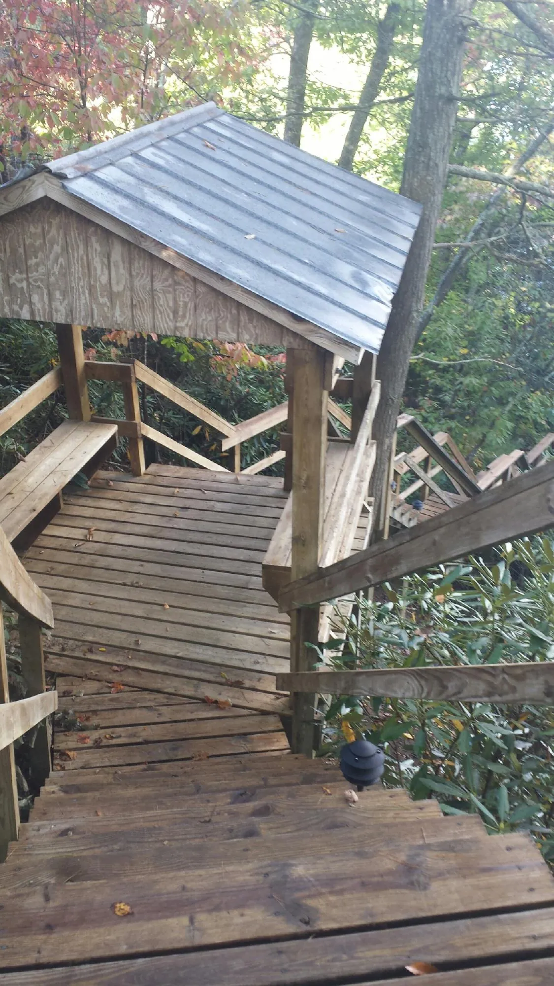 Metal roofed shelter over wooden steps on a wooded walkway — Skylight Repair & Installation work by our crew in Old Fort